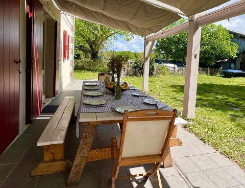 une table en bois assise sur une terrasse avec une table dans l'établissement Grande maison entre Lac et forêt, à Gastes