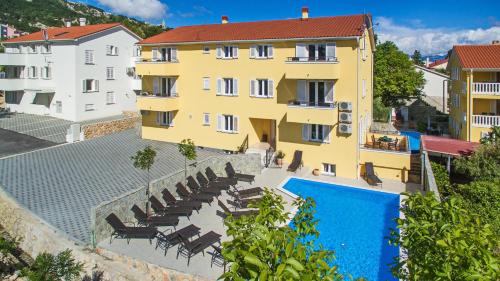 a hotel with a swimming pool and a yellow building at Apartments Gorica 2 in Baška