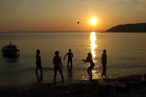 a group of people playing on the beach at sunset at Apartments Gorica 2 in Baška