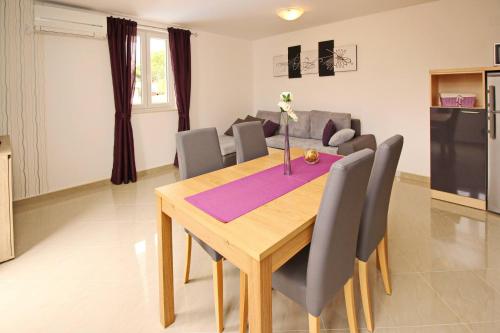a dining table and chairs in a living room at Apartments Gorica 2 in Baška