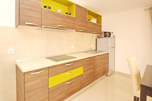 a kitchen with wooden cabinets and a refrigerator at Apartments Gorica 2 in Baška