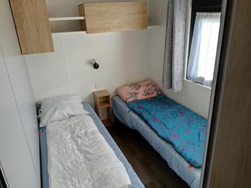 une petite chambre avec deux lits et une fenêtre dans l'établissement Mobile-home bord de mer, au Guilvinec