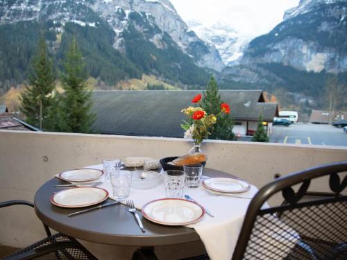 una mesa con platos y vasos en un balcón con montañas en Apartment Chalet Abendrot apARTments-18 by Interhome, en Grindelwald
