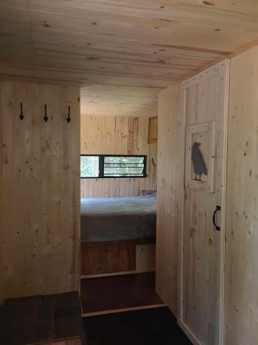 a small room with a bed in a wooden house at #5 Le Repère Aux Corbeaux in Saint-Onésime