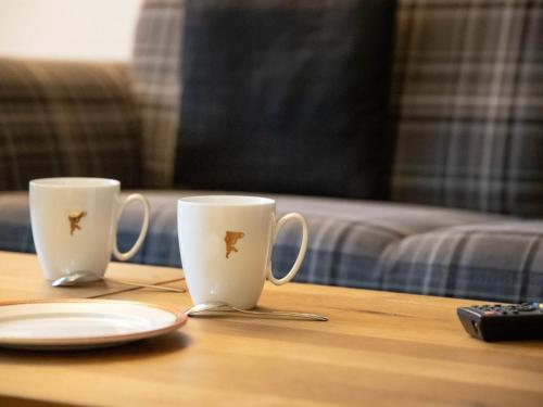 two coffee cups sitting on a table with a plate at Apartment Chalet Abendrot apARTments-28 by Interhome in Grindelwald