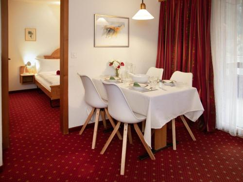 a room with a table with white chairs and a bed at Apartment Chalet Abendrot apARTments-21 by Interhome in Grindelwald