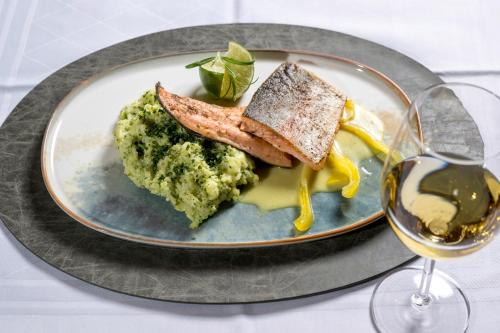 a plate of food with bread and broccoli and a glass of wine at Hotel am Haslinger Hof in Bad Füssing