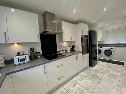 a kitchen with white cabinets and a black refrigerator at Glynn House in Newport