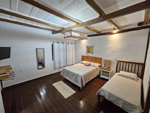 a bedroom with two beds and a television in it at Hospedaria do Engenho in Niterói