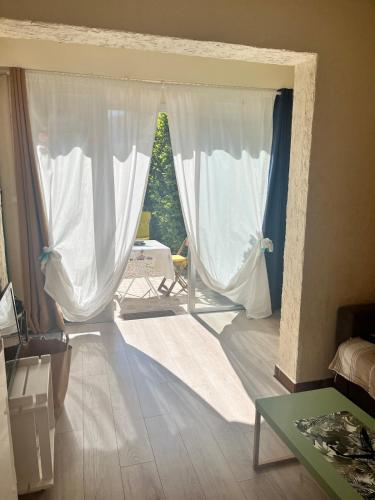 - un salon doté d'une grande fenêtre avec des rideaux blancs dans l'établissement Studio climatisé avec entrée privée- 5 min des plages, sur les hauteurs de Cavalaire, à Cavalaire-sur-Mer