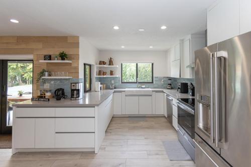 a kitchen with white cabinets and a stainless steel refrigerator at Heated pool - 5min Coral Gables - Family Vacation in Miami