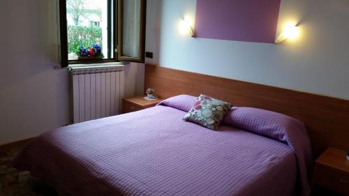 a bedroom with a bed with purple sheets and a window at Albergo Vecchio Forno in Spoleto