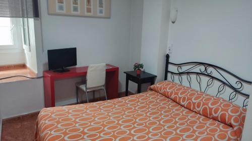 a bedroom with a bed and a desk and a television at Pension Segura in Murcia
