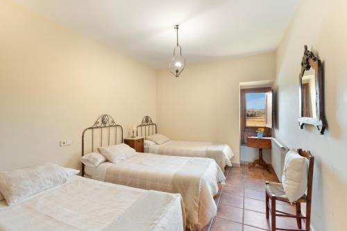 a bedroom with two beds and a chair and a window at Cal Cirera in Sagás