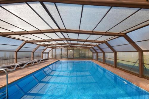 an indoor swimming pool with a glass roof at Cal Cirera in Sagás