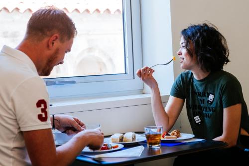 a man and a woman sitting at a table eating food at Boutique Hostel Forum in Zadar