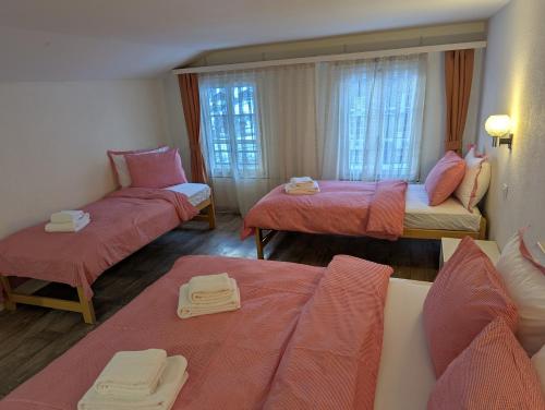 a room with three beds with pink sheets at Hotel Schützen Lauterbrunnen in Lauterbrunnen