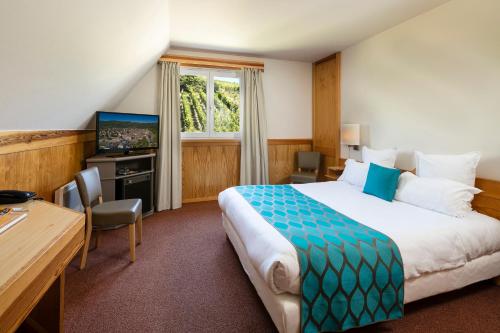 a hotel room with a bed and a desk and a television at Best Western Plus Hotel & SPA Le Schoenenbourg in Riquewihr