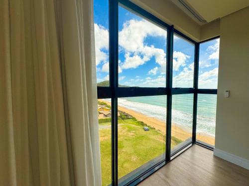 a room with a large window with a view of the ocean at Blue Sea Hotel in Itapema