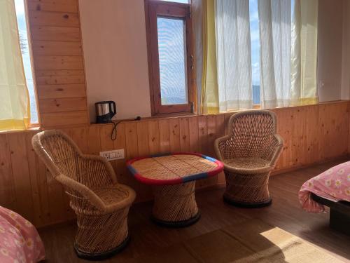 a room with three chairs and a table in it at Countryside Apple orchard by LivingStone in Shimla