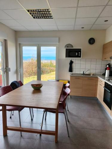 - une cuisine avec une table en bois et une vue sur l'océan dans l'établissement Maisonjoske, à Beaulieu