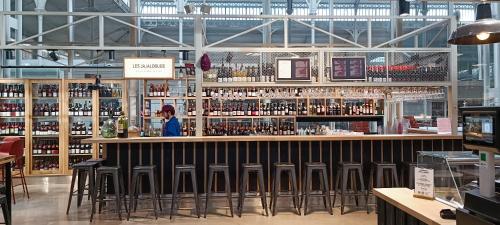 une femme debout dans un bar d'un magasin de vin dans l'établissement Les Halles superbe studio 4 personnes Wi-Fi Climatisation Netflix cœur de ville et historique, à Béziers