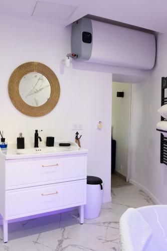 La salle de bains est pourvue d'une commode blanche et d'un miroir. dans l'établissement Le Palmier Doré - Calme à Menton jusqu'à 4 personnes, à Menton