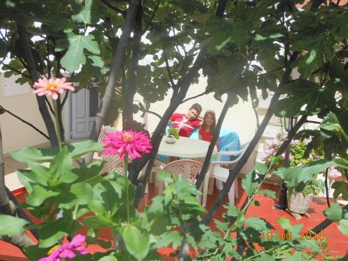 two girls sitting at a table in a garden at Lorena Rooms in Risan