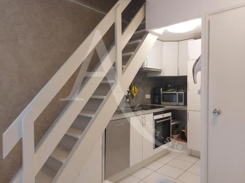 un escalier dans une cuisine avec des placards blancs dans l'établissement T2 avec espace nuit en mezzanine et 2 terrasses, à Sète