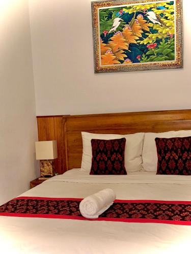 a bedroom with a bed with a picture on the wall at Intan Guest House in Ubud