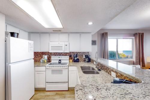a kitchen with white appliances and a large window at Camelot by the Sea - Oceana Resorts Vacation Rentals in Myrtle Beach