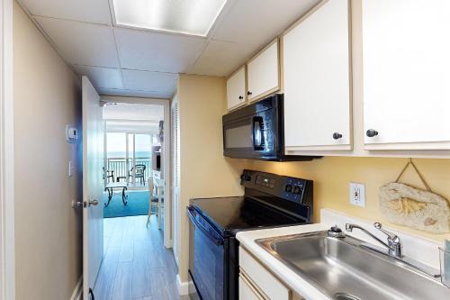a kitchen with a sink and a microwave at Camelot by the Sea - Oceana Resorts Vacation Rentals in Myrtle Beach
