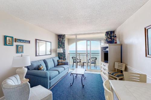 a living room with a blue couch and a table at Camelot by the Sea - Oceana Resorts Vacation Rentals in Myrtle Beach