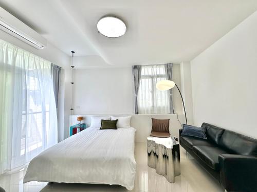 a white bedroom with a bed and a couch at 窩想想 Wo Style Inn 包棟 停車位 & 電動麻將 & 頂樓星星 in Taitung City