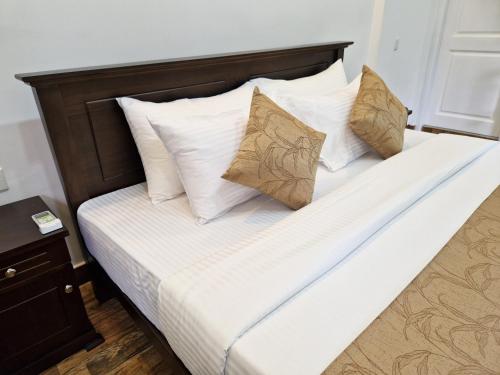 a bed with white sheets and pillows in a room at Villa Sole in Kandy