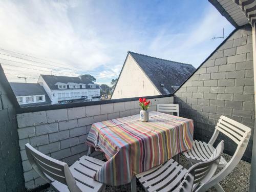 a table and chairs on a balcony with a table and flowers at Apartment Les Embruns-1 by Interhome in Carnac
