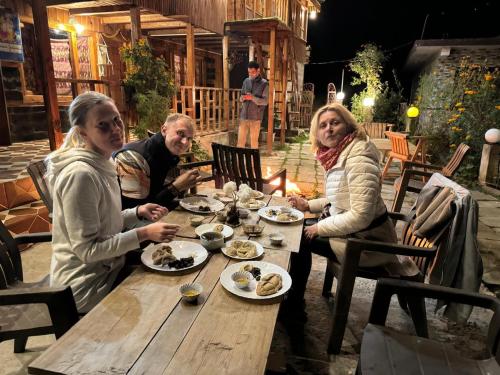 a group of people sitting at a table eating food at Rustic wood house - A village home stay in Jibhi Valley in Jibhi