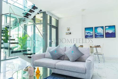a living room with a couch and a glass staircase at Bloomfields 2br Duplex Canal View Rahalofts in Abu Dhabi