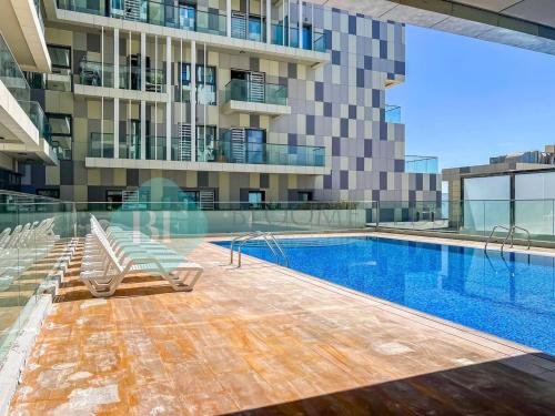 a swimming pool with two lounge chairs next to a building at Bloomfields 2br Duplex Canal View Rahalofts in Abu Dhabi