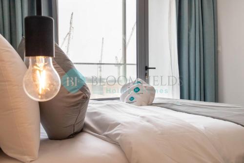 a bedroom with a bed with a lamp and a window at Bloomfields Euphoric Stu In Oasis Masdar City in Al Qurayyah