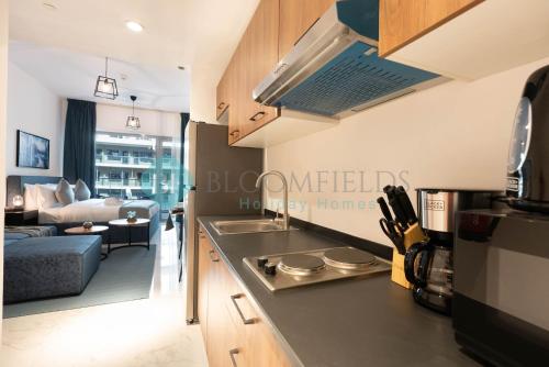 a kitchen with a sink and a living room at Bloomfields Euphoric Stu In Oasis Masdar City in Al Qurayyah