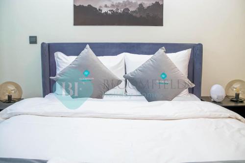 a bed with white sheets and pillows at Bloomfields Cozy Stu Azizi Riviera Meydan in Dubai
