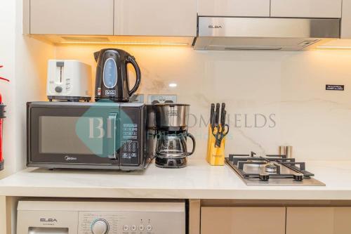 a kitchen counter with a microwave and a stove at Bloomfields Cozy Stu Azizi Riviera Meydan in Dubai