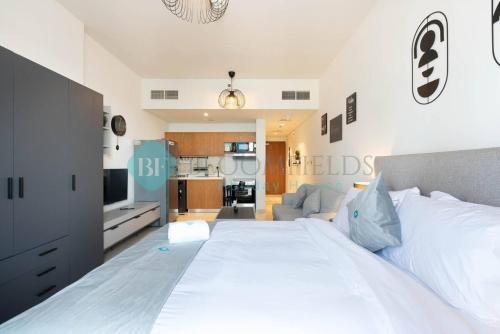 a bedroom with a large white bed and a kitchen at Bloomfields Premium Stu Canal View Julphar Tower in Abu Dhabi