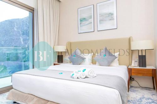 a bedroom with a large white bed with a window at Bloomfields Iconic 2br & Maid Address Beach Resort in Fujairah