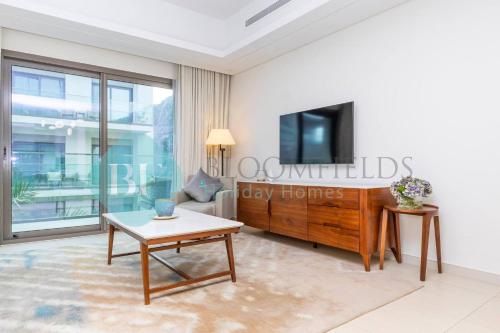 a living room with a tv and a table at Bloomfields Iconic 2br & Maid Address Beach Resort in Fujairah