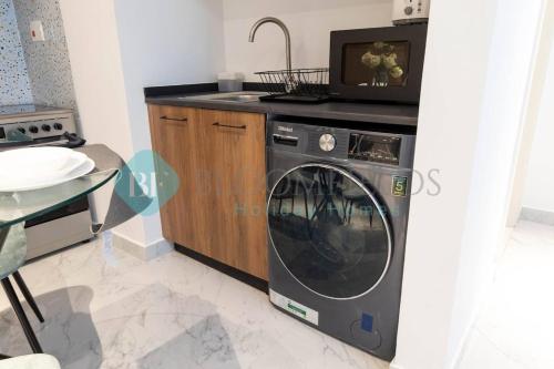a kitchen with a washing machine and a tv at Bloomfields Stylish 1br In Oasis Masdar City in Al Qurayyah