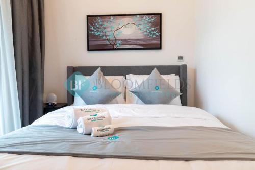 a bed with two complimentary pillows on it at Bloomfields Stylish 2br In Oasis Masdar City in Al Qurayyah