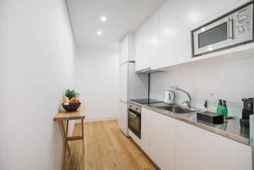a kitchen with white cabinets and a wooden table at D'Autor Apartments Sá da Bandeira in Porto