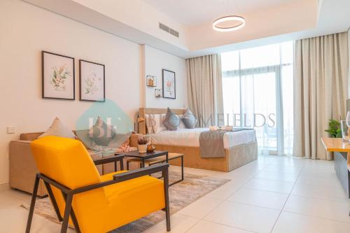 a living room with a bed and a yellow chair at Bloomfields Spacious Stu In Thalassa Beach Front in Abu Dhabi